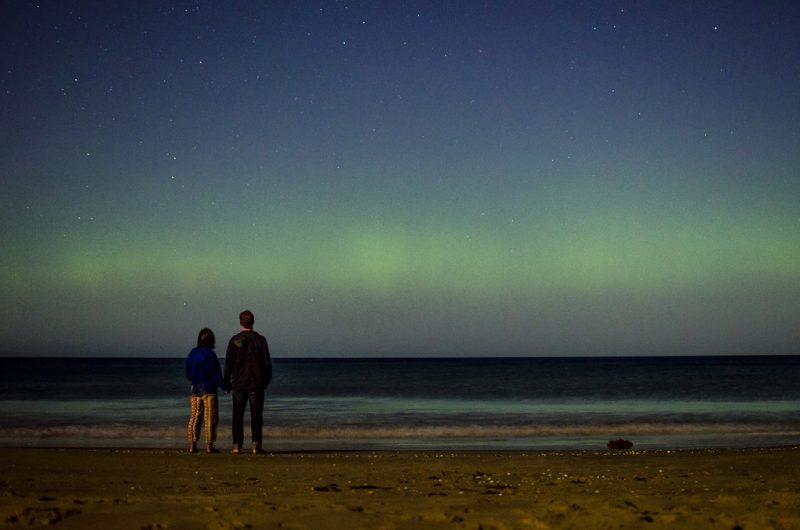 People watching the southern lights by a beach in Tasmania
