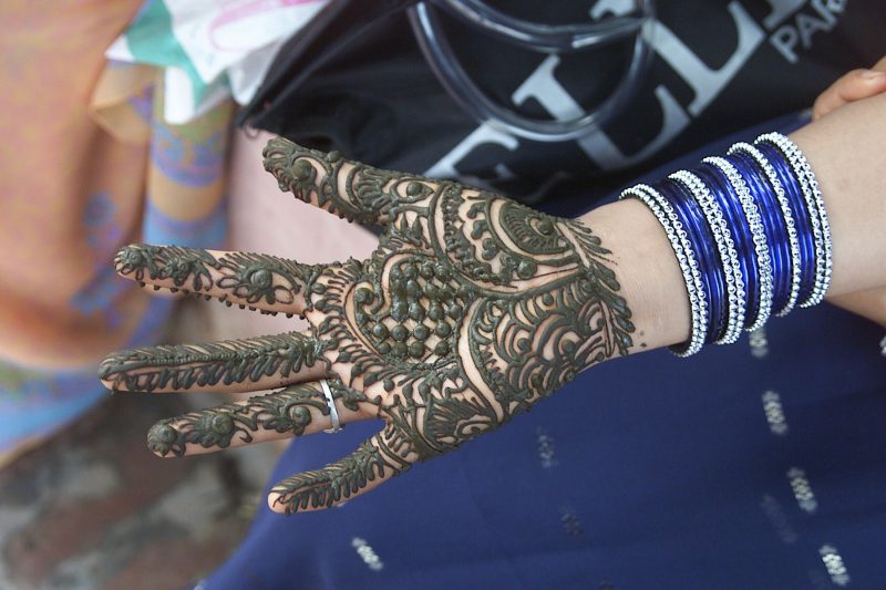 A woman adorning her hand with Heena